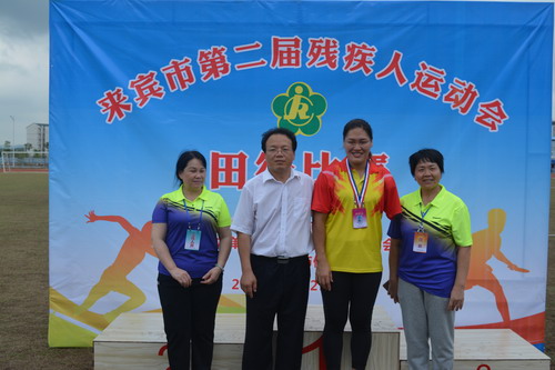 图为来宾市残联理事长黄小波(左二)与女子铅球项目金牌获得者黄甜甜(右二)合影